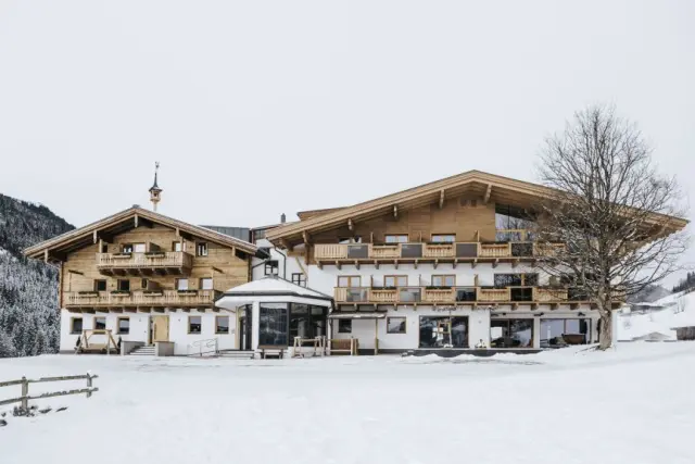 Aussenansicht des Thurnerhof Hotels im Winter mit traditioneller Holzarchitektur und verschneiter Landschaft.