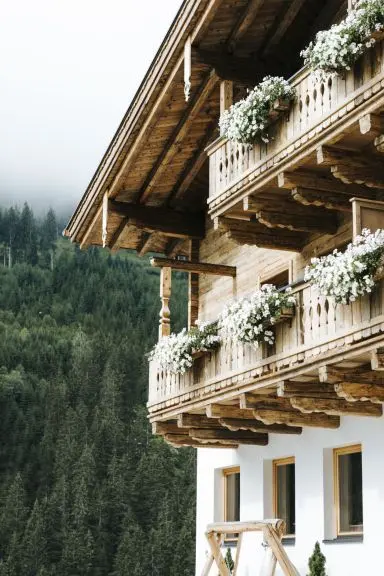 Traditionelle Holzfassade des Hotel Thurnerhof mit blumengeschmückten Balkonen und bewaldetem Berghintergrund.
