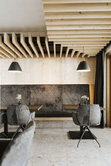 Gemütlicher Restaurantbereich im Hotel Thurnerhof mit Holzakzenten, bequemen Sitzbänken und modernen Pendelleuchten.