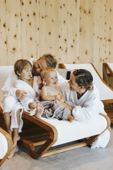 Glückliche Familie in Bademänteln entspannt auf Liegen im Wellnessbereich des Hotel Thurnerhof. Familienfreundliches Spa-Erlebnis.