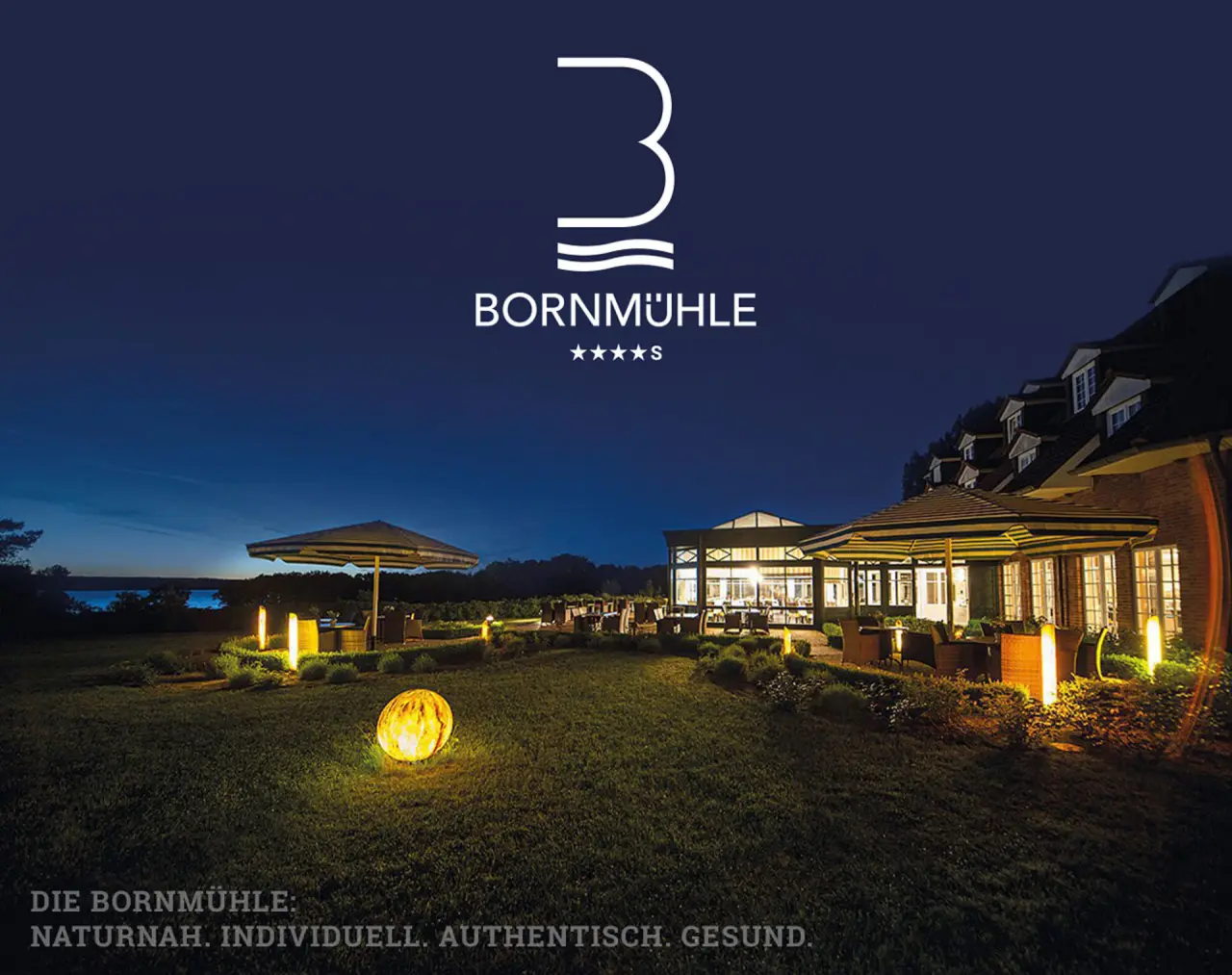 Abendansicht des Hotel Bornmühle mit beleuchteter Terrasse, Garten und See im Hintergrund. Idyllische Atmosphäre.