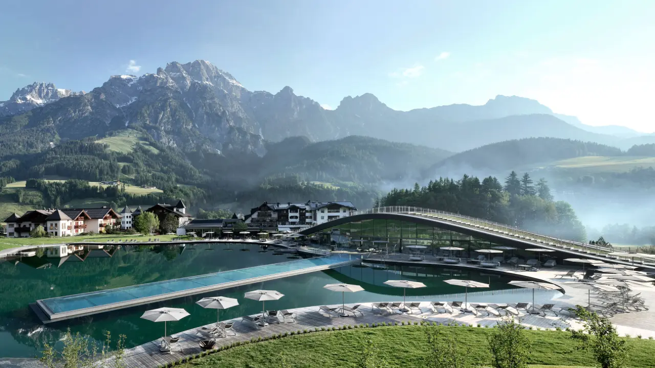 Panoramablick auf den Infinity Pool, Naturbadeteich und das Wellnesshotel Krallerhof mit Alpenkulisse.