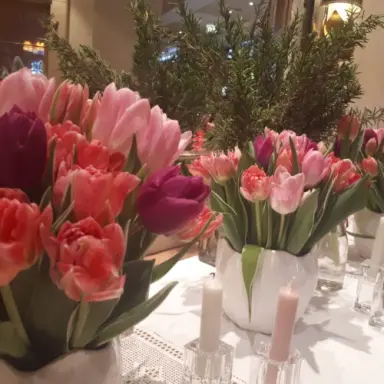 Frische Tulpen in verschiedenen Rosa- und Rottönen mit Kerzen als Tischdekoration im Hotel Post Lermoos.