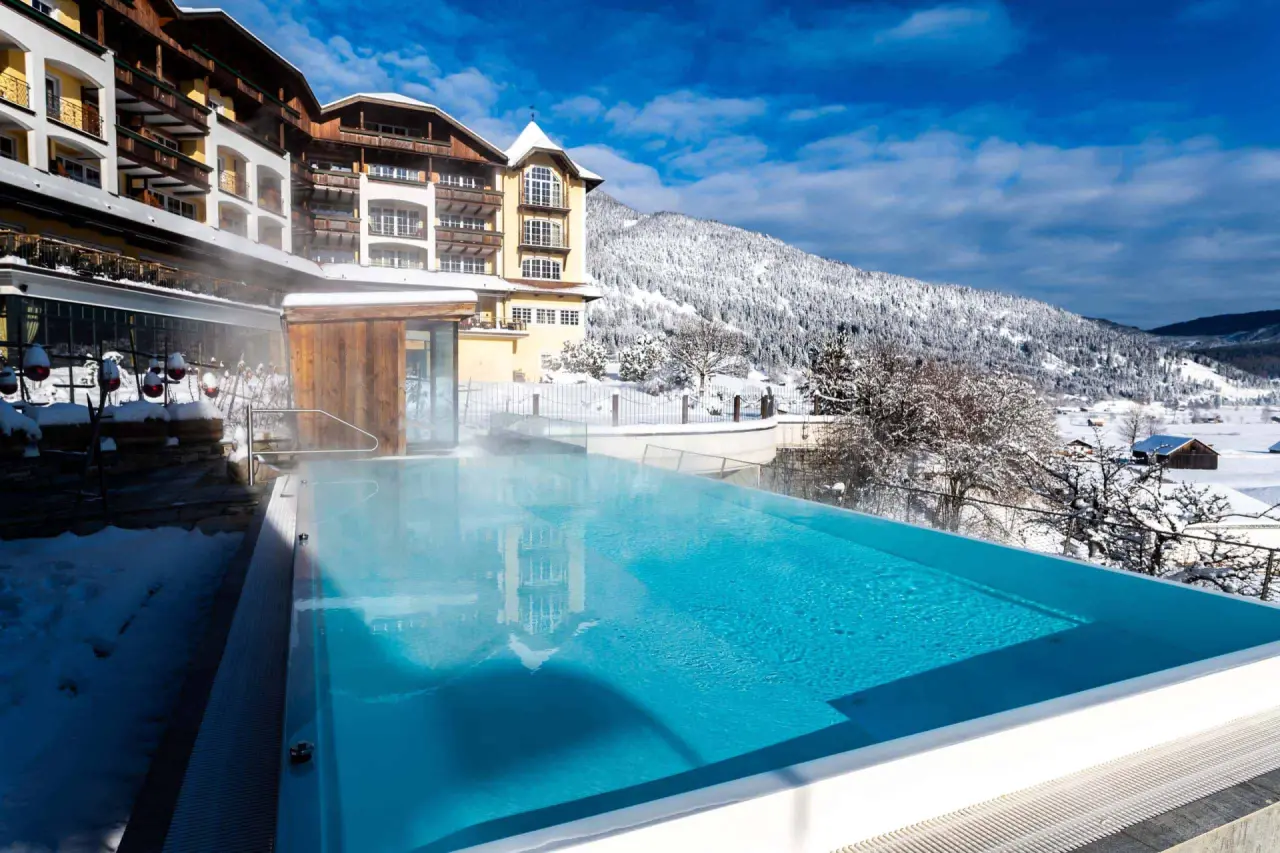Beheizter Infinity-Aussenpool mit Dampf und Blick auf die verschneiten Berge im Hotel Post Lermoos im Winter.
