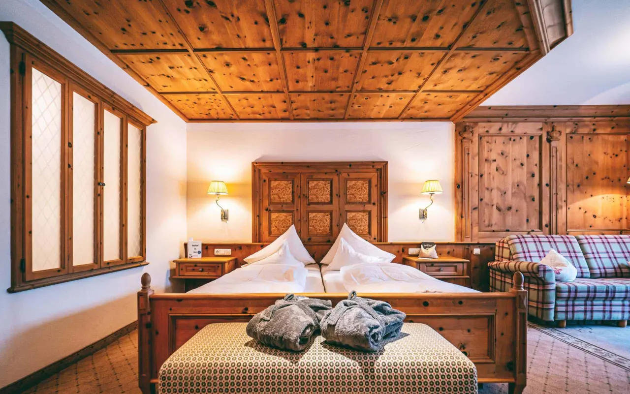 Gemütliches Doppelzimmer im alpinen Stil mit Holzdecke und Bademänteln im Hotel Post Lermoos