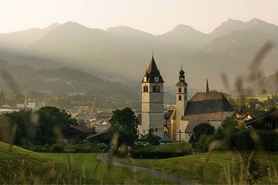 Hotel Kitzhof Mountain Design Resort in Kitzbühel – Malerische Stadtansicht mit Kirche und Bergen | Wellnesshotel Tirol