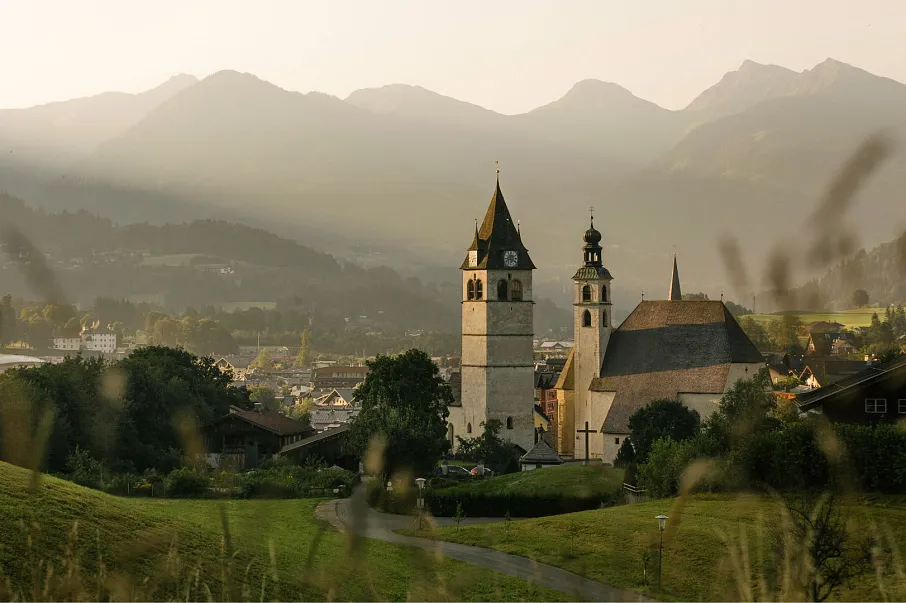 Hotel Kitzhof Mountain Design Resort in Kitzbühel – Malerische Ansicht von Kitzbühel mit Kirche und Bergen | Wellnesshotel Tirol