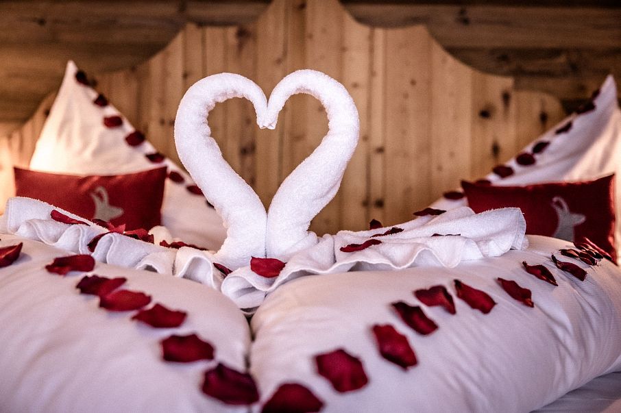 Hotel Kitzhof Mountain Design Resort in Kitzbühel – Romantisch dekoriertes Bett mit Handtuchschwänen | Wellnesshotel Tirol