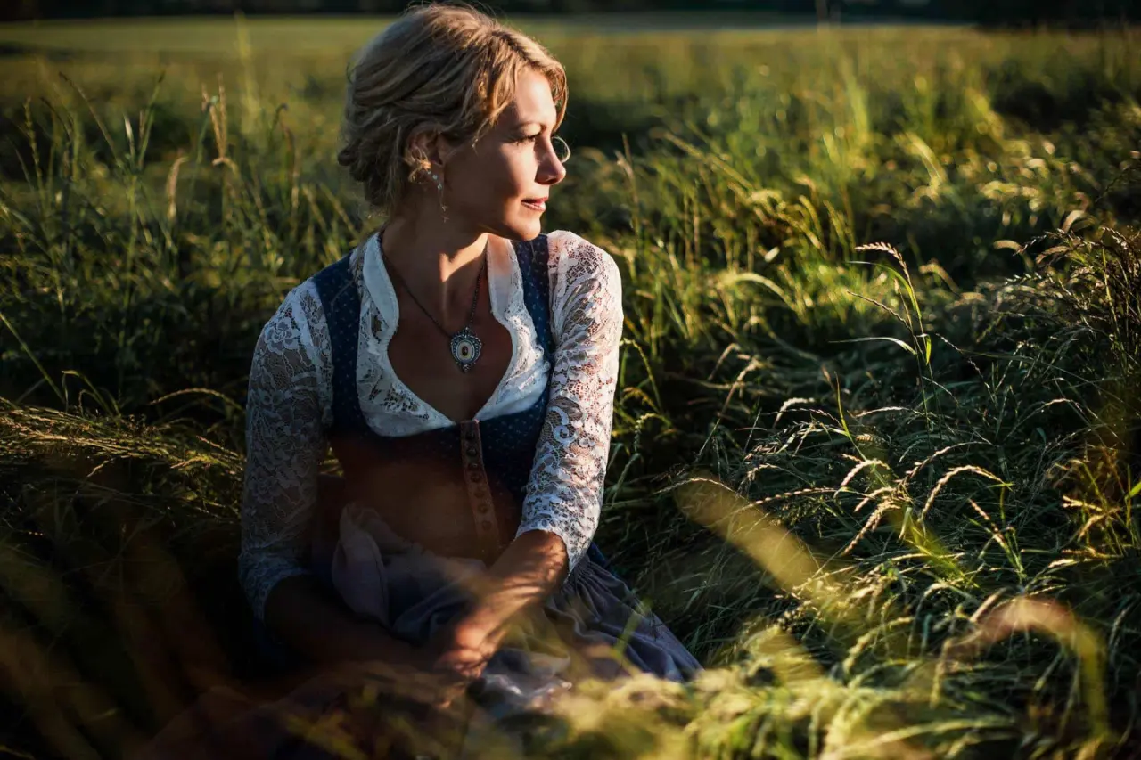Porträt einer Frau im Dirndl in einer sonnigen Wiese, Wellness Natur Resort Gut Edermann.