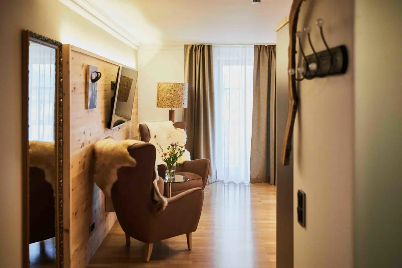 Gemütlicher Wohnbereich in einer Suite des Wellness Natur Resort Gut Edermann mit Holzwand, Sesseln und Tageslicht.