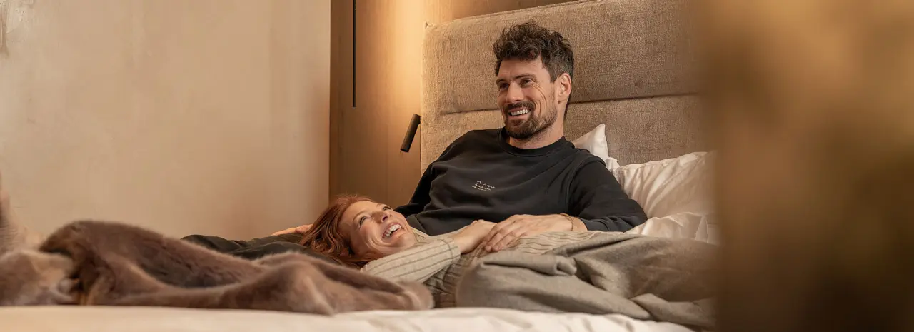 Glückliches Paar entspannt im modernen Doppelzimmer des Hotel Post Kaltenbach. Gemütliche Atmosphäre für einen erholsamen Aufenthalt.