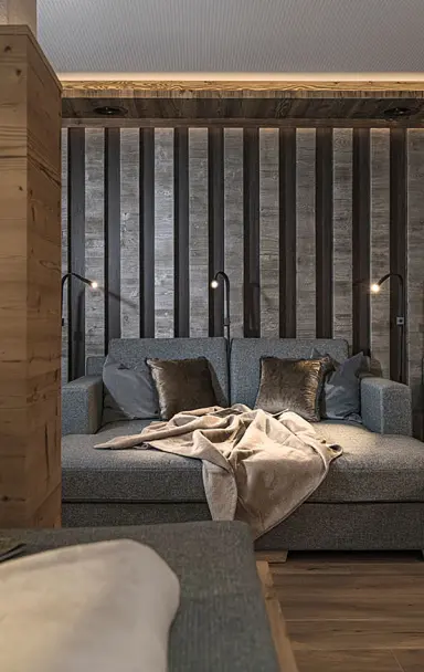 Moderne Entspannungsliege mit Holzwand und indirekter Beleuchtung im Spa-Bereich des Hotel Post Kaltenbach.
