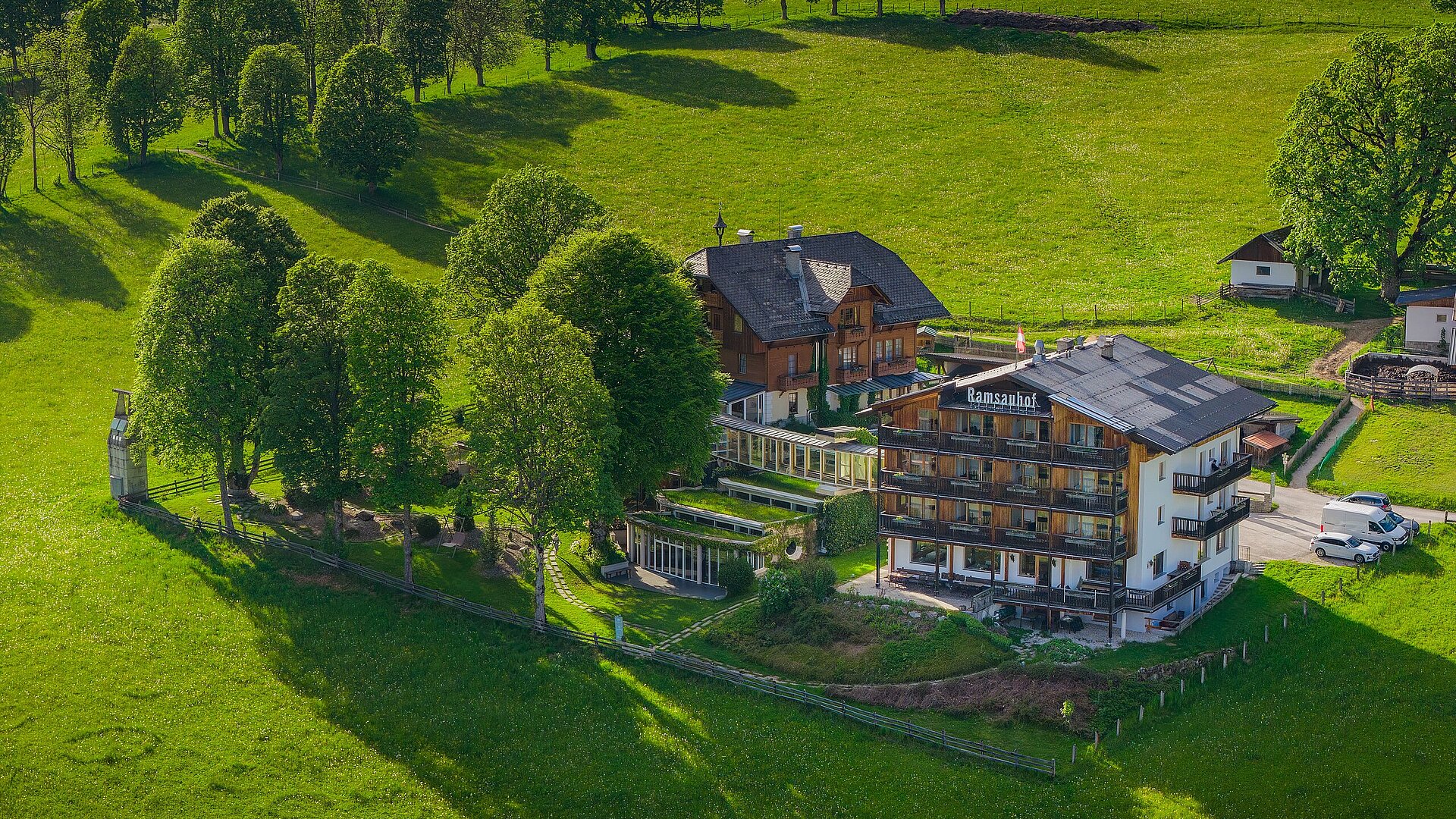 Hotel Ramsauhof in Ramsau am Dachstein – Luftaufnahme im Sommer mit grünen Wiesen und Bäumen | Wellnesshotel Dachsteinregion
