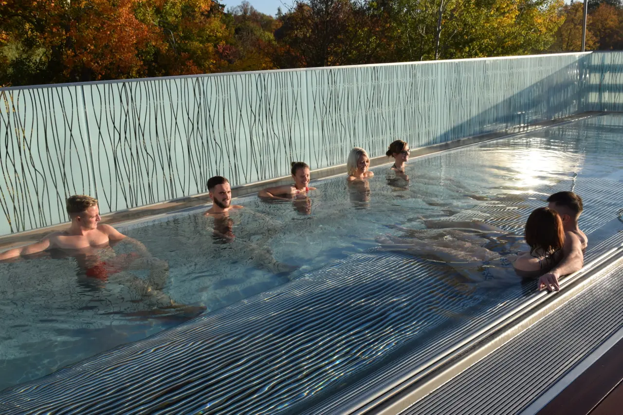 Gäste entspannen im Aussenpool des relexa hotel Bad Steben mit Blick auf herbstliche Bäume.