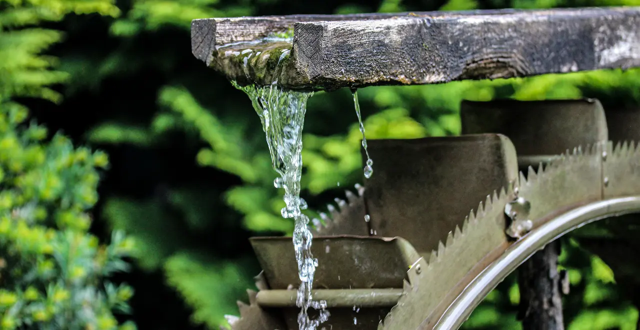 Detailaufnahme eines Wasserspiels mit Holzrinne und Wasserrad im Garten des Gesundheits- und VitalCenter Gollée.