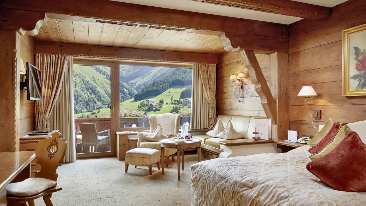 Luxuriöses Doppelzimmer im alpinen Stil mit Balkon und Panoramablick auf die Berge im Relais & Chateaux Hotel Singer.