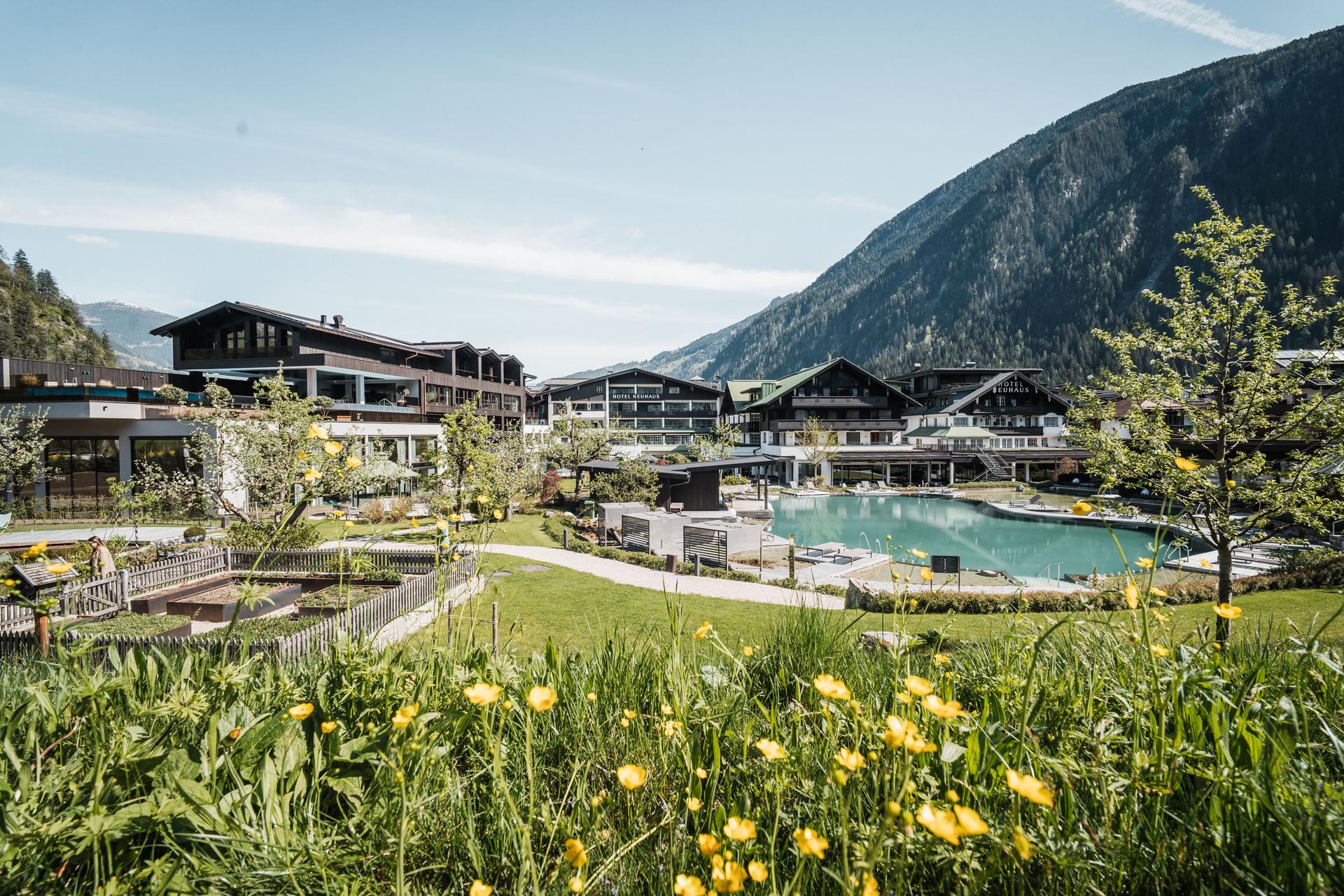 Neuhaus Zillertal Resort in Mayrhofen – Außenansicht des Hotels mit Garten und Naturbadeteich | Wellnesshotel Zillertal