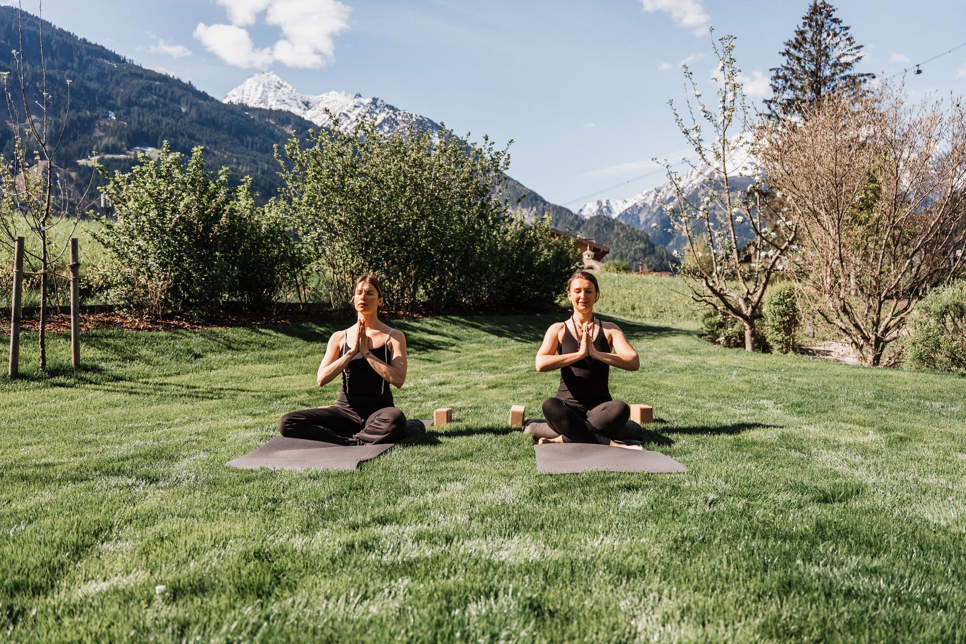 Neuhaus Zillertal Resort in Mayrhofen – Zwei Frauen beim Yoga im Freien mit Bergblick | Wellnesshotel Zillertal