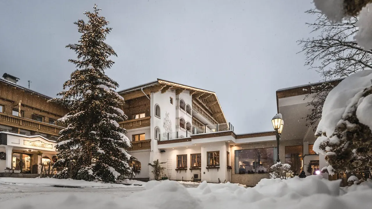 Festlich beleuchtetes Wohlfühlresort Peternhof im Winter mit verschneitem Weihnachtsbaum und warmen Lichtern.