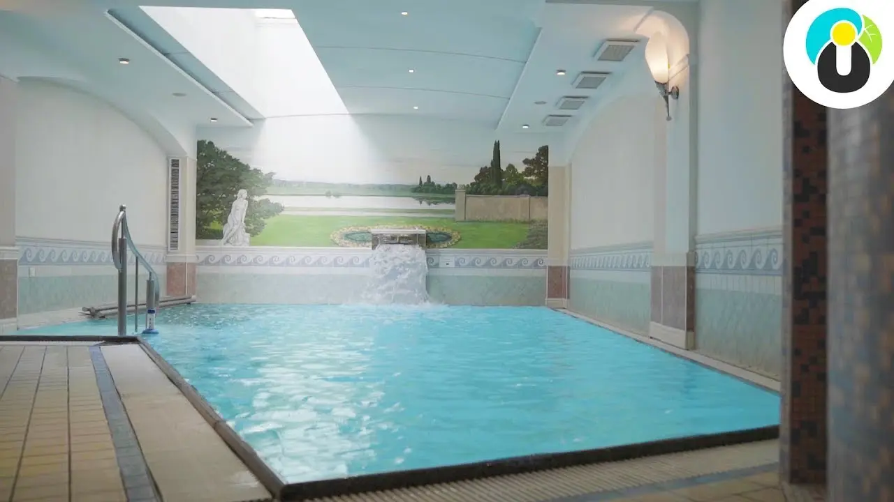 Innenpool mit kleinem Wasserfall und klassischer Wandmalerei im Wellnessbereich des Hotel Das Reiners.