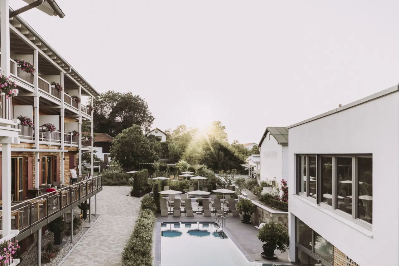 Aussenpoolbereich mit Sonnenliegen und Hotelbalkonen im Hotel St. Florian bei Abendsonne.