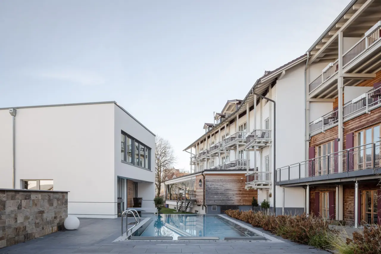 Aussenpool des Hotel St. Florian mit moderner und traditioneller Architektur im Hintergrund.
