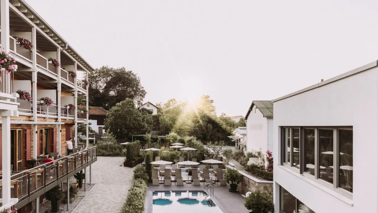 Sonnenverwöhnter Aussenpoolbereich des Hotel St. Florian mit bequemen Liegen, umgeben von grünen Gärten und Hotelgebäuden.