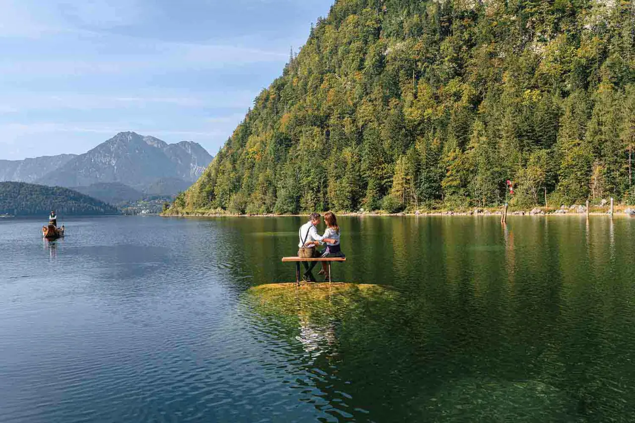 Romantisches Paar auf einer Bank im Grundlsee mit Bergpanorama, ideal für Entspannung im Romantik Hotel Seevilla.