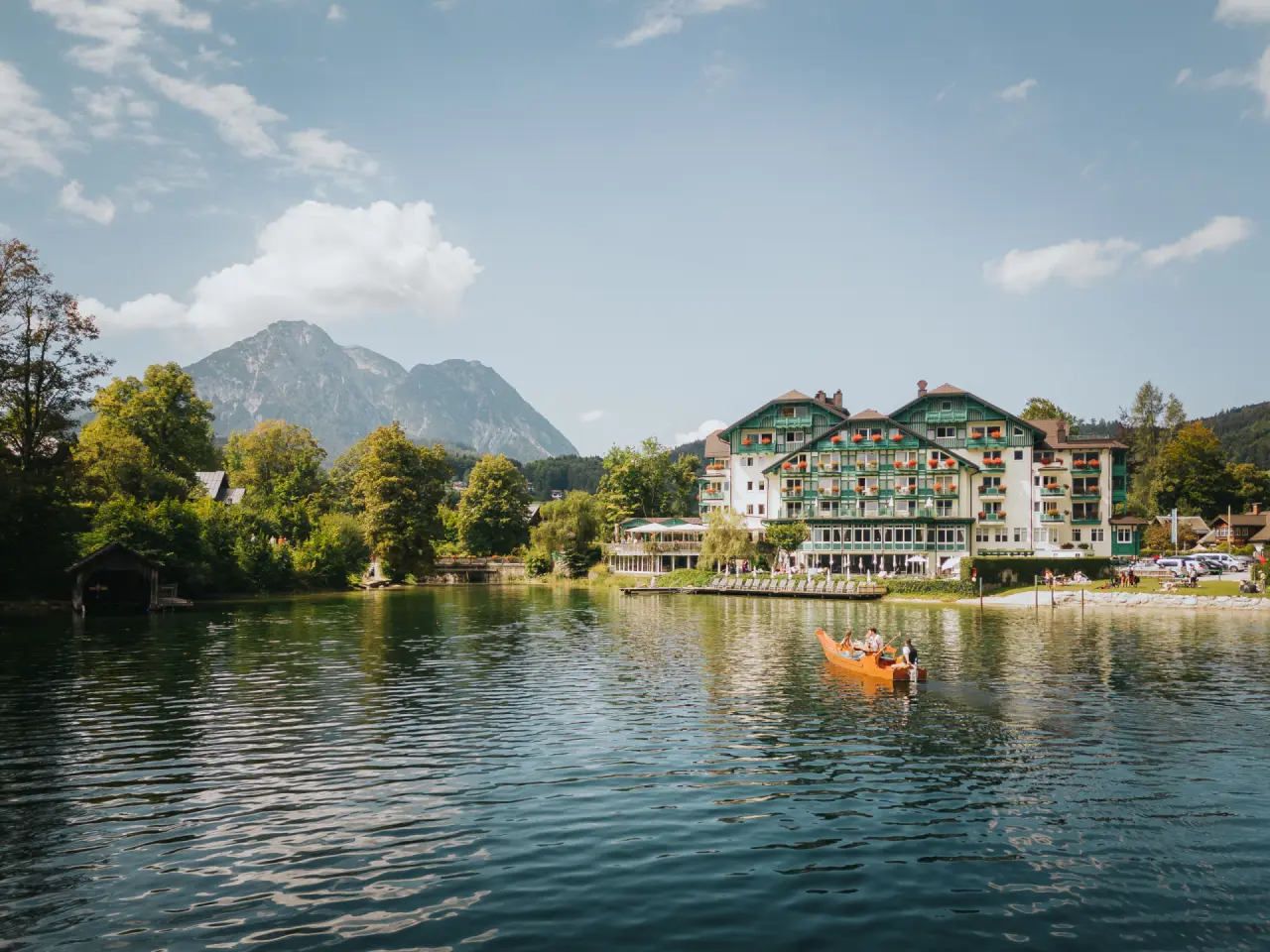 Romantik Hotel Seevilla am Grundlsee mit traditioneller Architektur, umgeben von Bergen und grüner Natur.