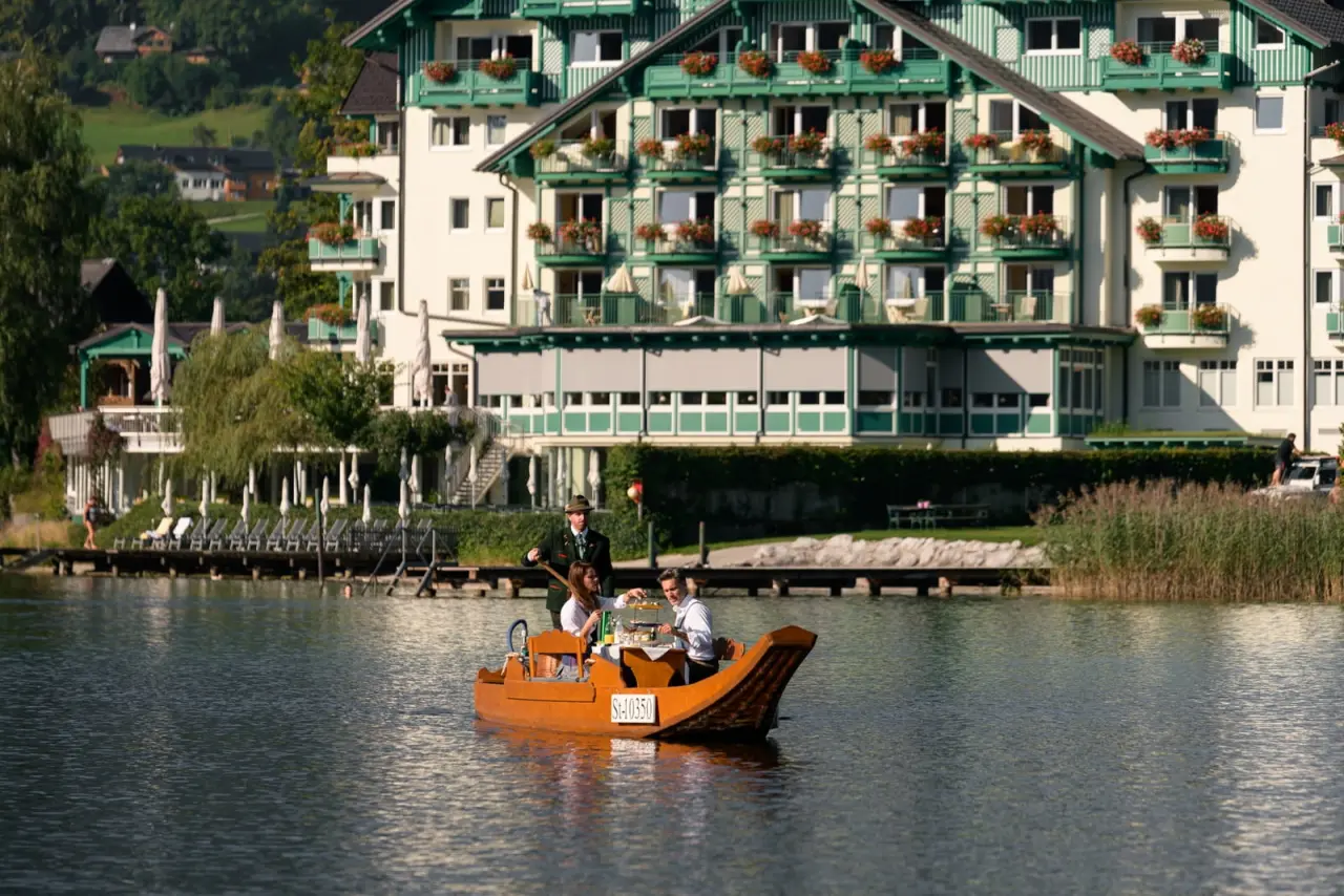 Romantik Hotel Seevilla am Altausseer See: Gäste genießen eine Bootsfahrt mit Service vor der malerischen Hotelfassade.