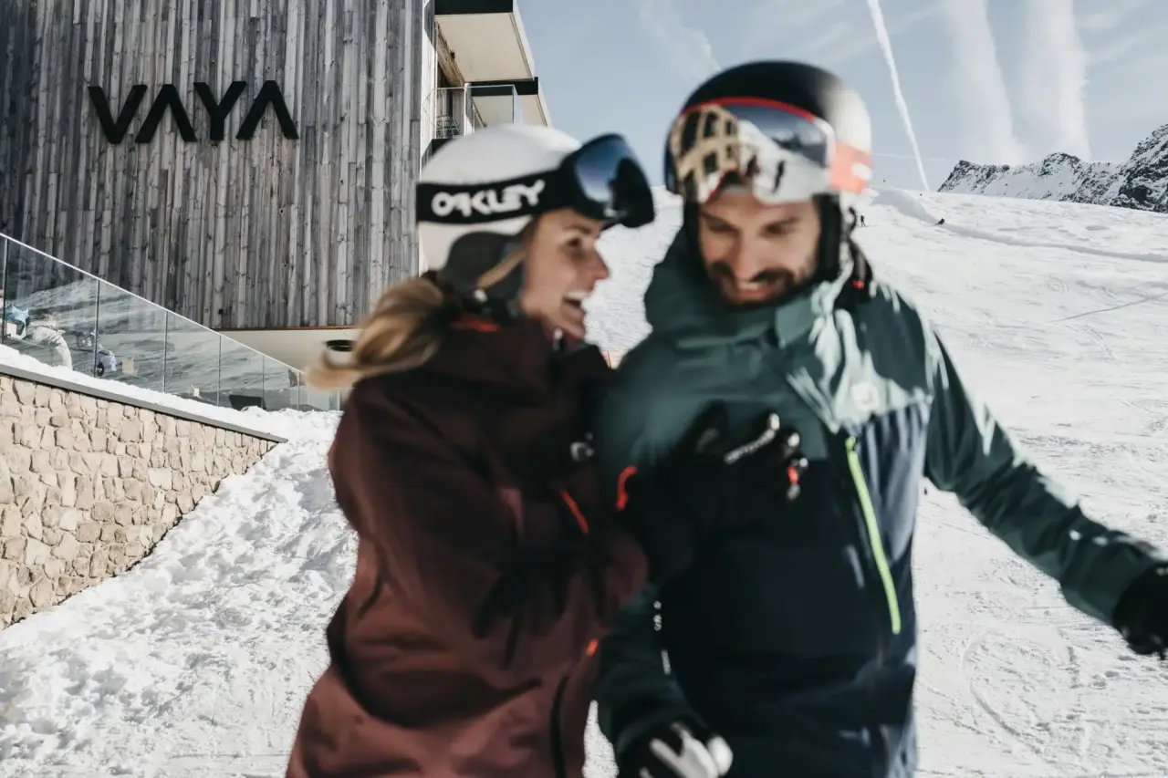 Skifahrer vor dem modernen Hotel The Crystal VAYA Unique in den verschneiten Alpen. Winterurlaub mit Bergblick.