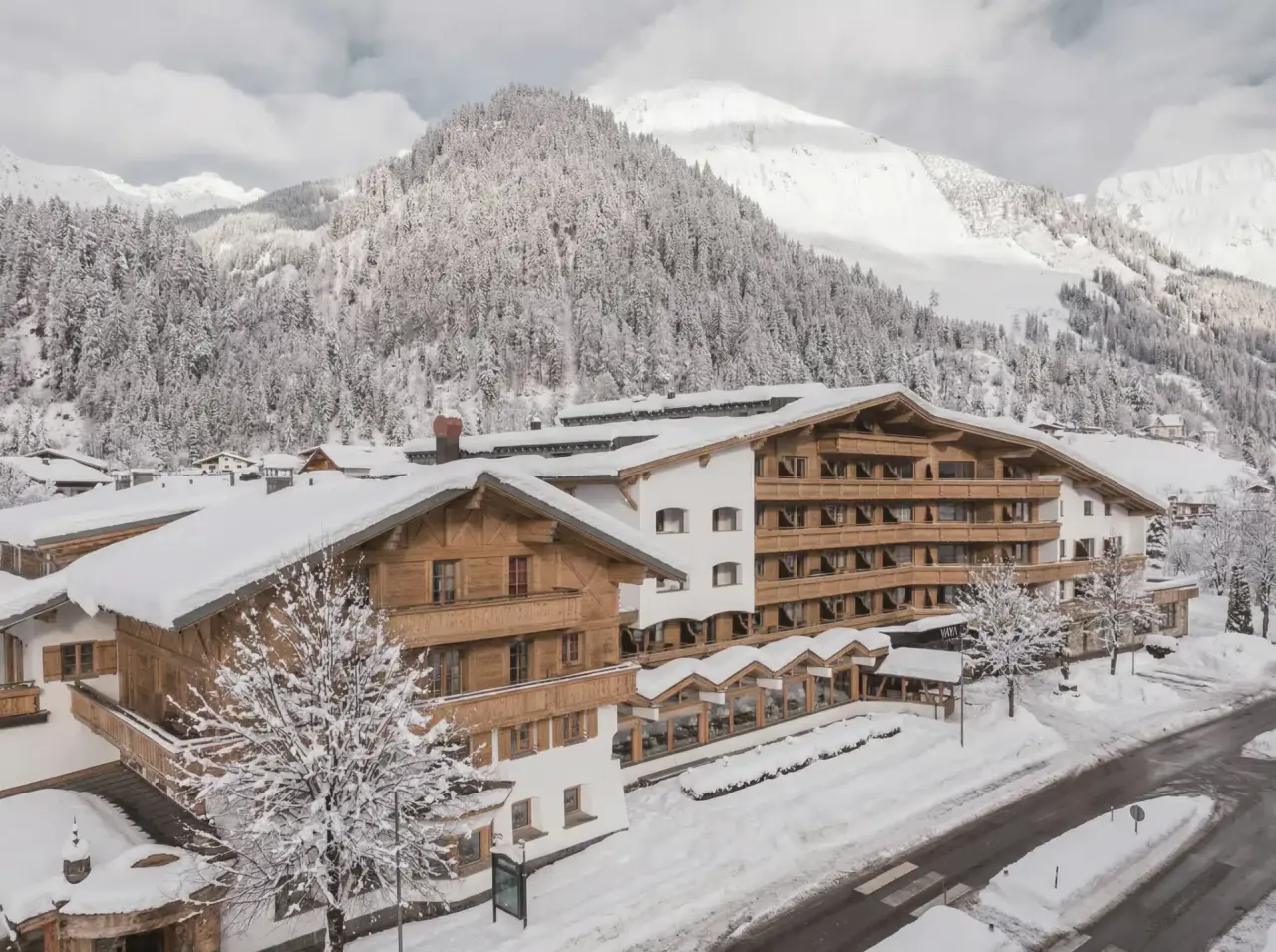 Winterliche Aussenansicht des The Crystal VAYA Unique Hotels in den verschneiten Alpen. Traditionelle Architektur umgeben von Bergen.