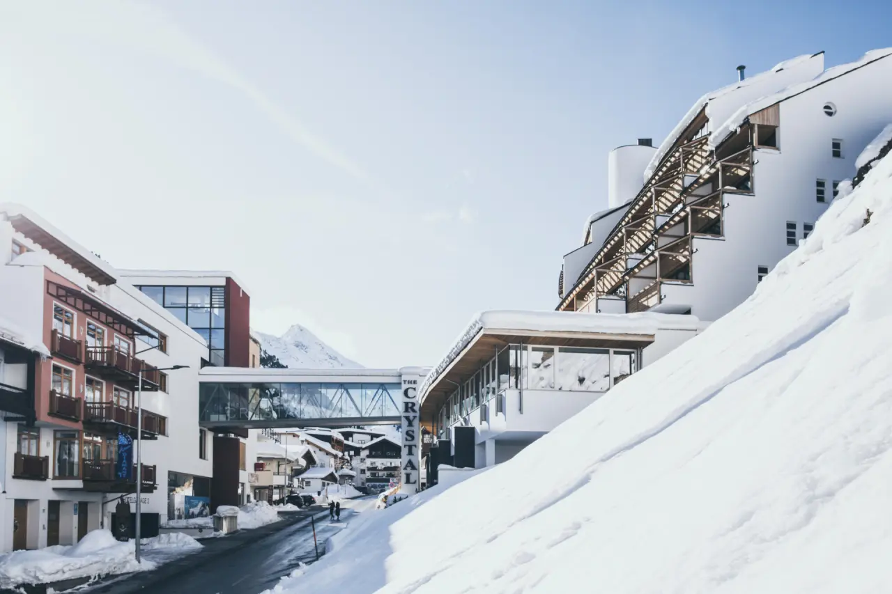 Winterliche Aussenansicht des modernen The Crystal VAYA Unique Hotels in den Alpen, umgeben von Schnee und Bergpanorama.