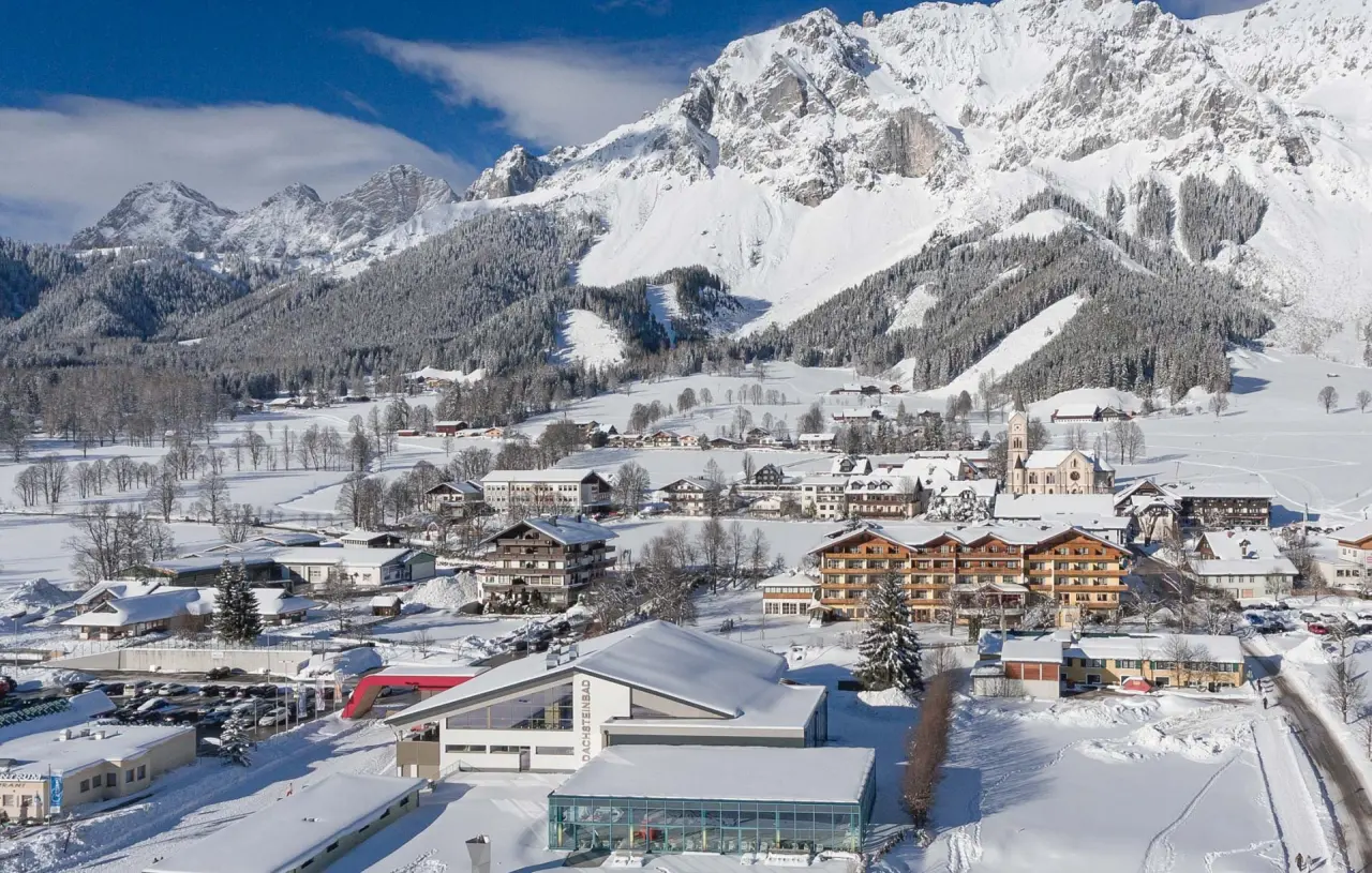 Winterpanorama des Hotel Matschner in Ramsau am Dachstein mit schneebedeckten Bergen, Dorf und dem Dachsteinbad.