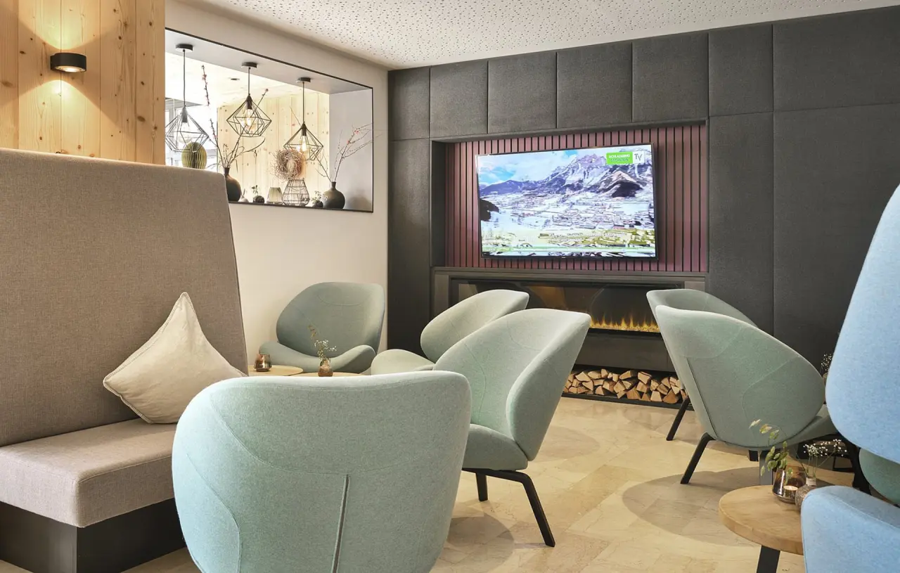 Moderne Hotellounge im Hotel Matschner mit bequemen Sesseln, Kamin und TV, ideal zum Entspannen.