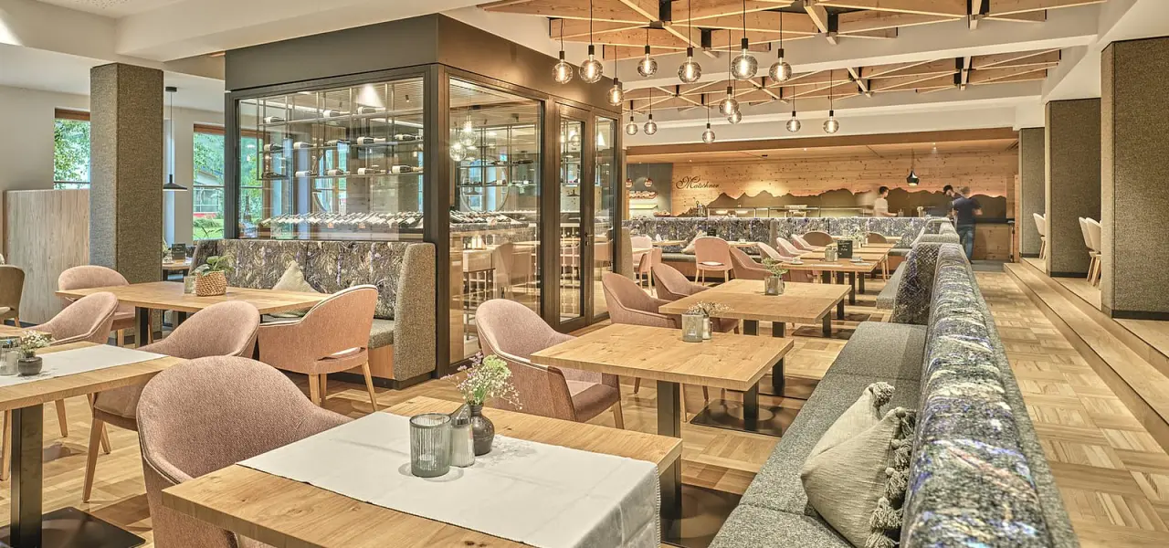 Modernes Restaurant im Hotel Matschner mit stilvoller Einrichtung, Holzelementen, gemütlichen Sitzbereichen und integriertem Weinkeller.