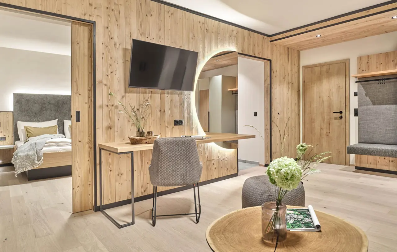 Modernes Hotelzimmer im alpinen Stil mit Holzelementen, Schreibtisch und Zugang zum Schlafbereich im Hotel Matschner.