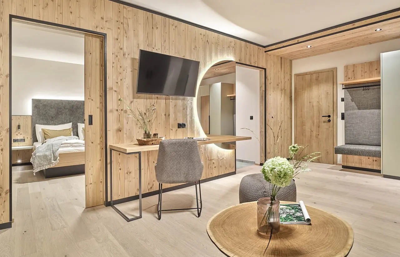 Moderne Suite im Hotel Matschner mit Holzelementen, Schlafbereich, Schreibtisch und gemütlicher Sitzecke.