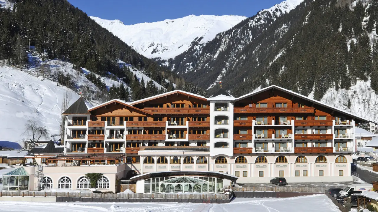 Wellness & Relax Hotel Milderer Hof in den verschneiten Alpen. Traditionelle Architektur vor imposantem Bergpanorama.