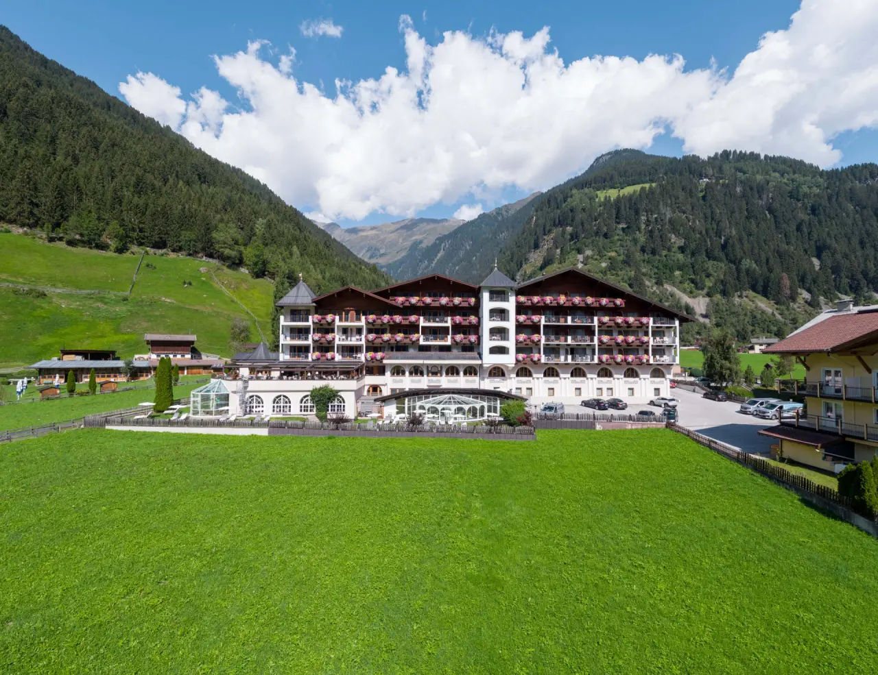 Aussenansicht des Wellness & Relax Hotel Milderer Hof im Stubaital mit blühenden Balkonen und Bergpanorama.