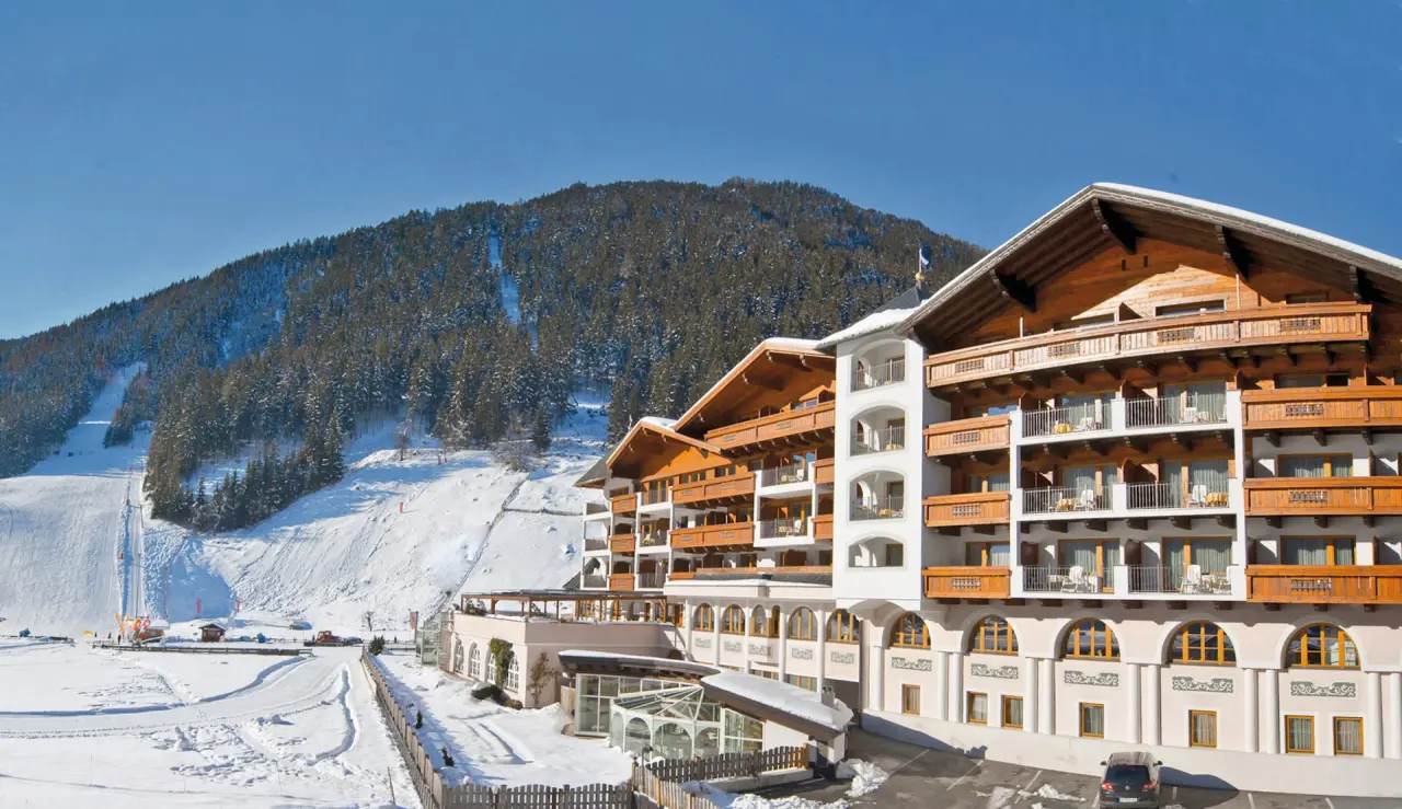 Aussenansicht des Wellness & Relax Hotel Milderer Hof im Winter mit verschneiten Bergen und Skipiste.