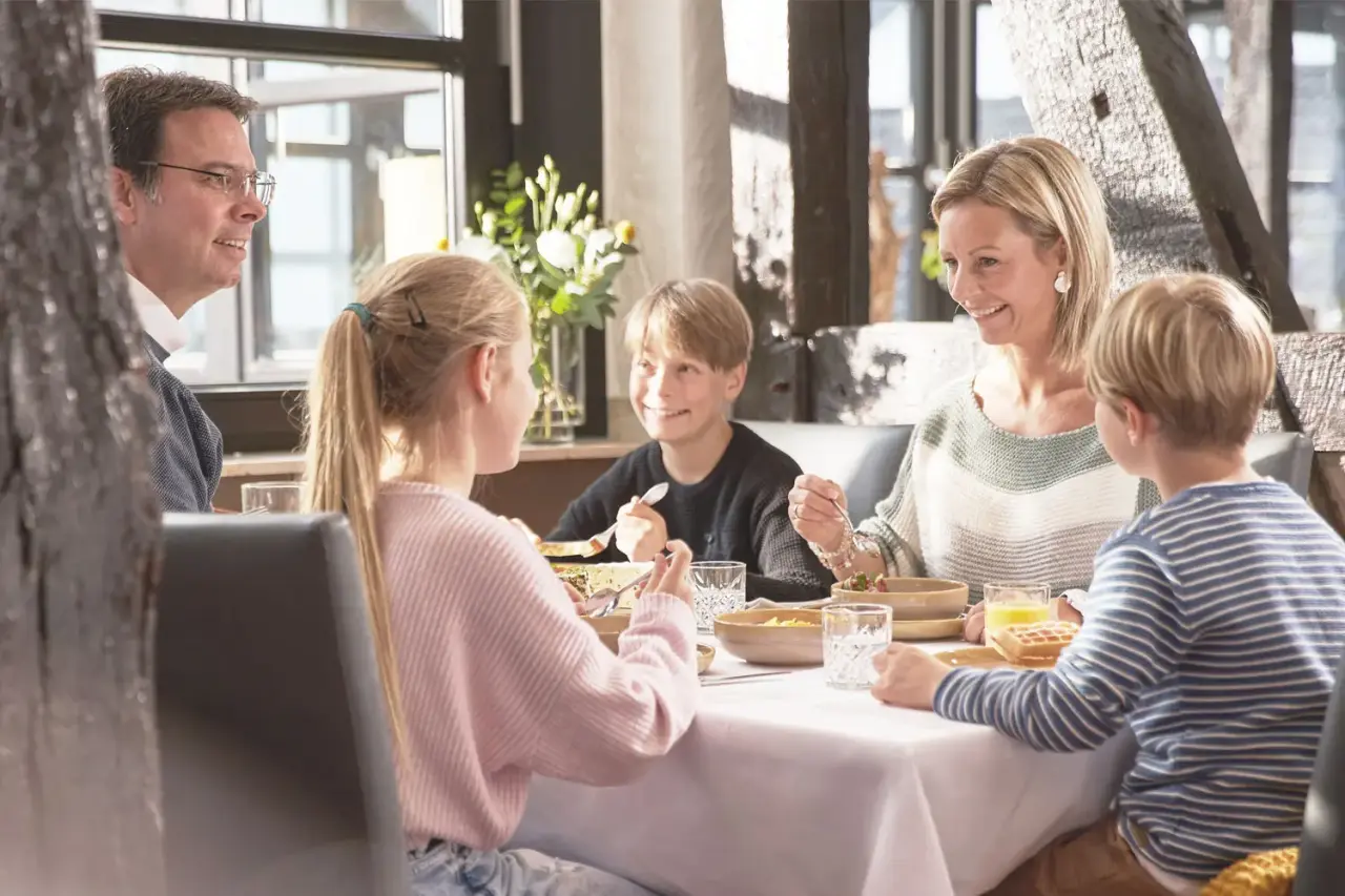 Glückliche Familie beim Frühstück im Restaurant des Sporthotels Grafenwald. Gemütliche Atmosphäre und leckeres Essen.