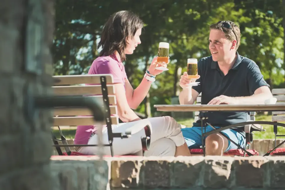 Gäste genießen erfrischendes Bier auf der sonnigen Restaurantterrasse des Sporthotel Grafenwald.