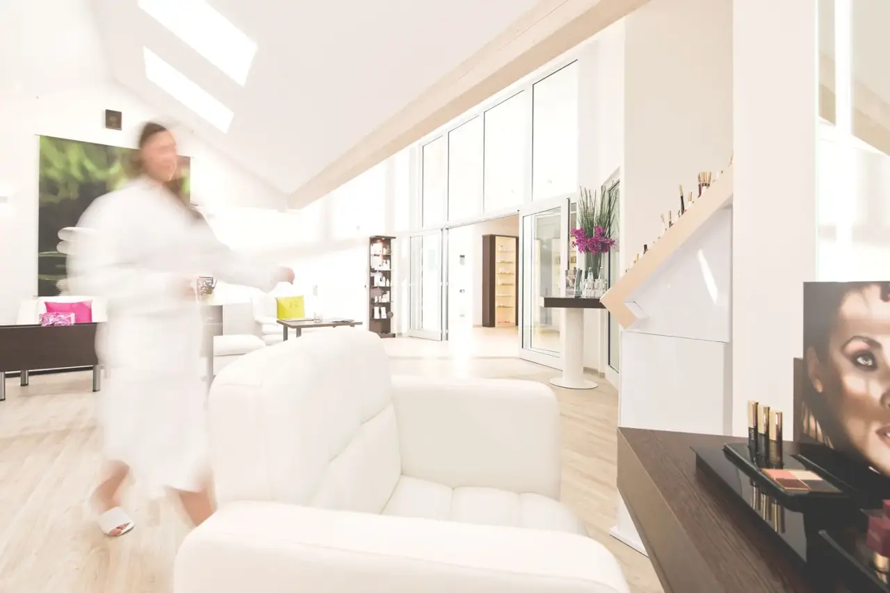 Heller Spa- und Beauty-Bereich im Sporthotel Grafenwald mit Kosmetikprodukten und einer Person im Bademantel.