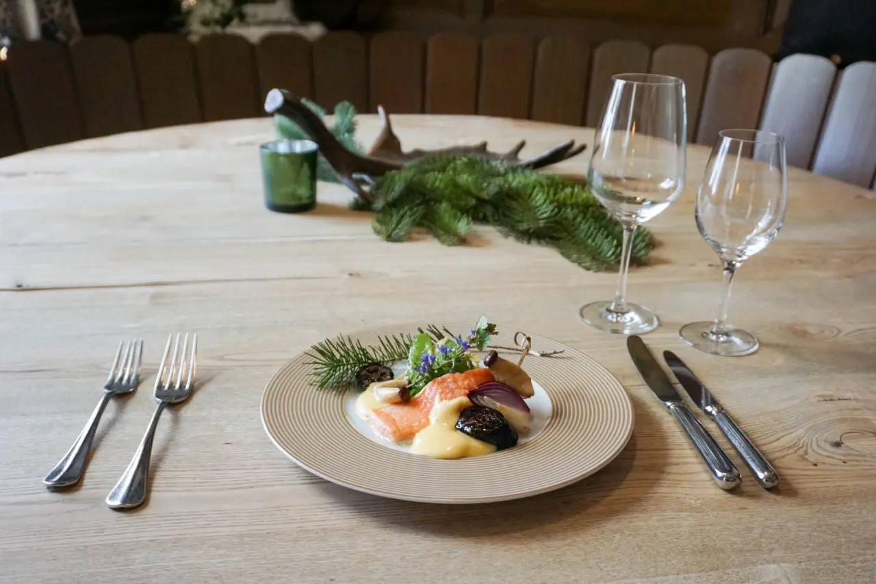 Ansprechend angerichteter Teller mit Lachs und Beilagen auf einem Holztisch im Restaurant des Waldhotel am Notschreipass.