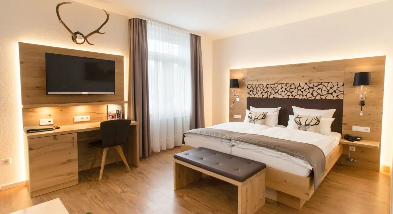 Gemütliches Doppelzimmer im Waldhotel am Notschreipass mit Holzelementen, Schreibtisch und indirekter Beleuchtung.