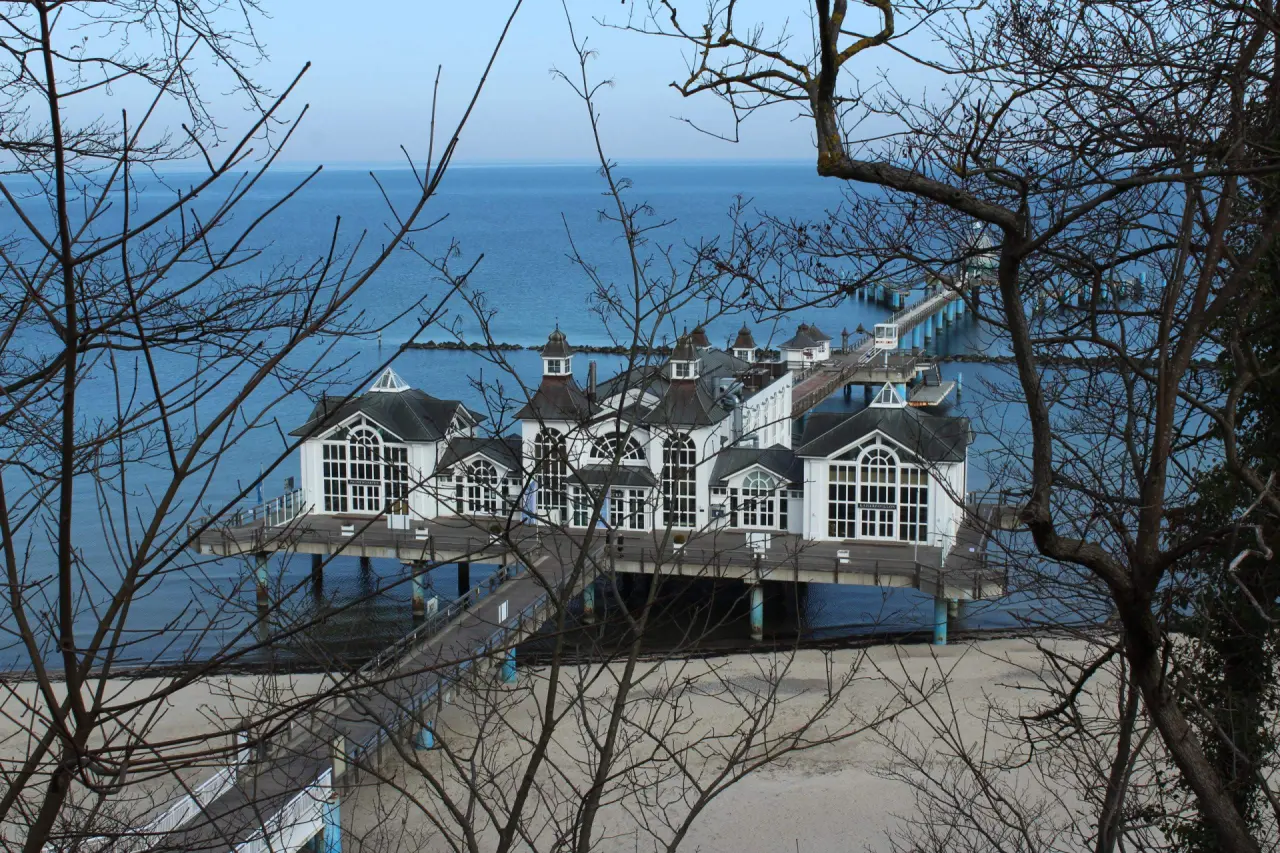 Historische Seebrücke mit Gebäuden und Strandblick am Meer, umrahmt von kahlen Bäumen, nahe Hotel Bernstein.