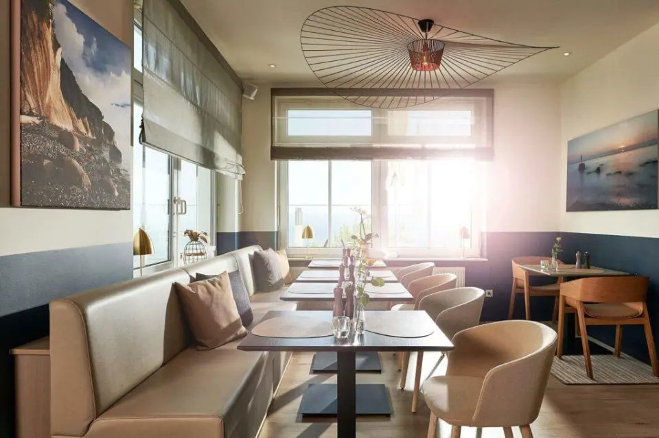 Helles Restaurant im Hotel Bernstein mit bequemen Sitzbänken, Tischen und Meerblick durch große Fenster.