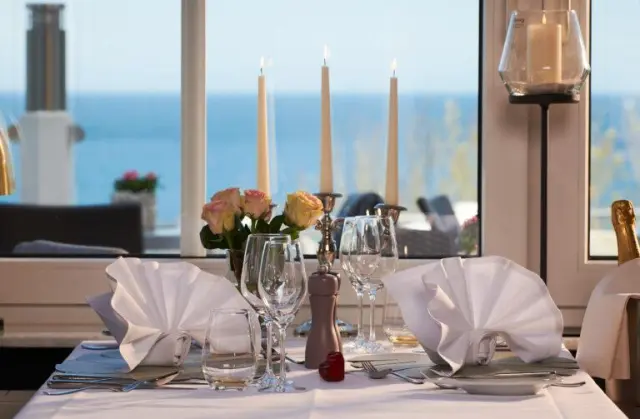 Romantisch gedeckter Tisch mit Meerblick im Restaurant des Hotel Bernstein, mit Kerzenlicht und Rosen.
