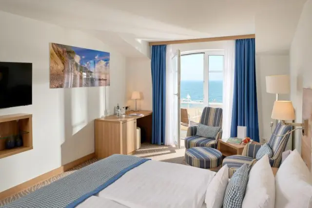 Helles Hotelzimmer im Hotel Bernstein mit Meerblick, Balkon und gemütlicher Sitzecke am Fenster.